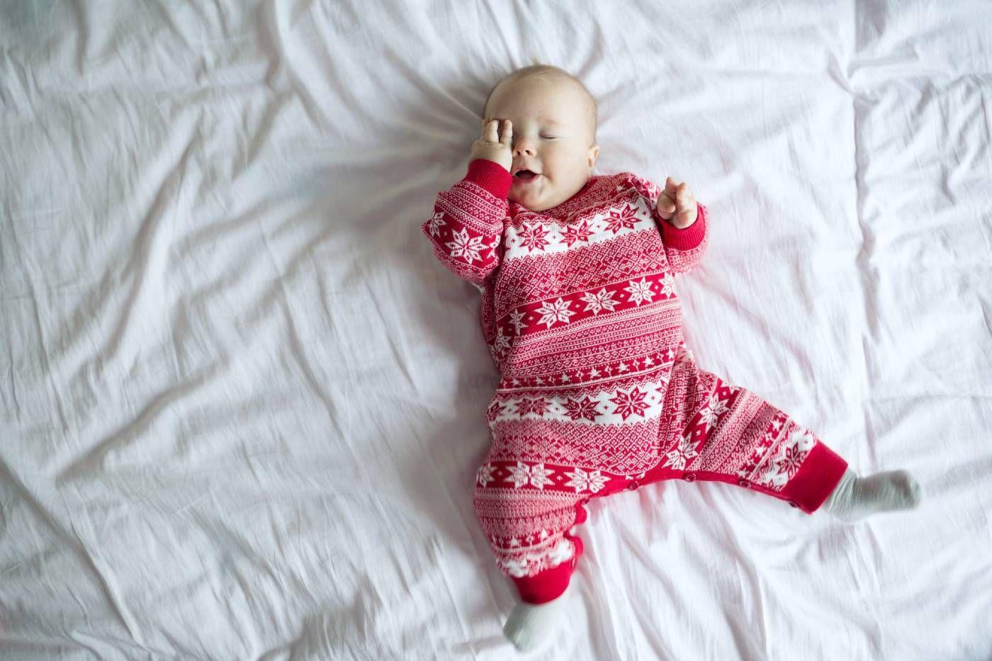 Sleepy baby on a bed wearing holiday PJs