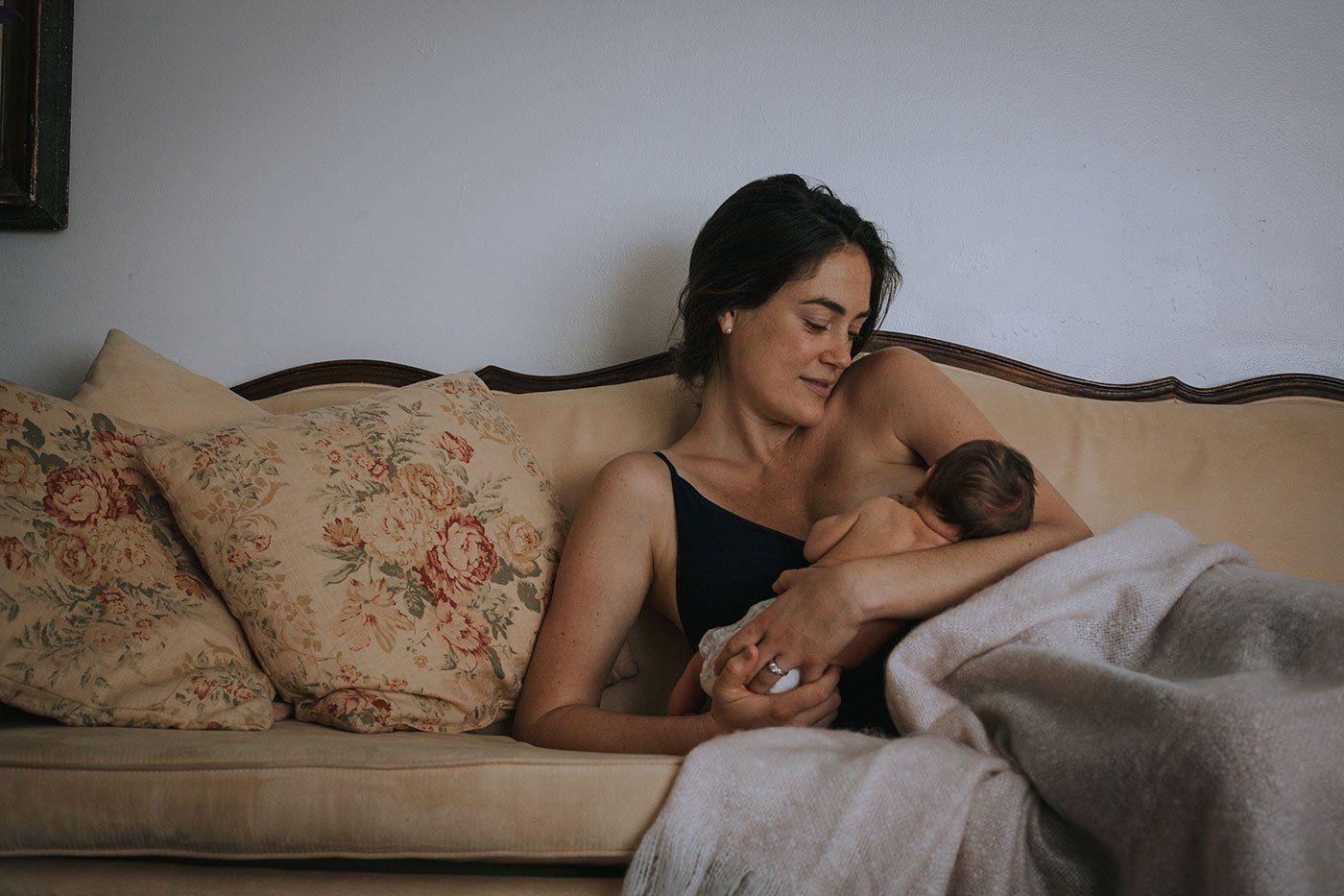 Mom breastfeeding baby in her arms on couch