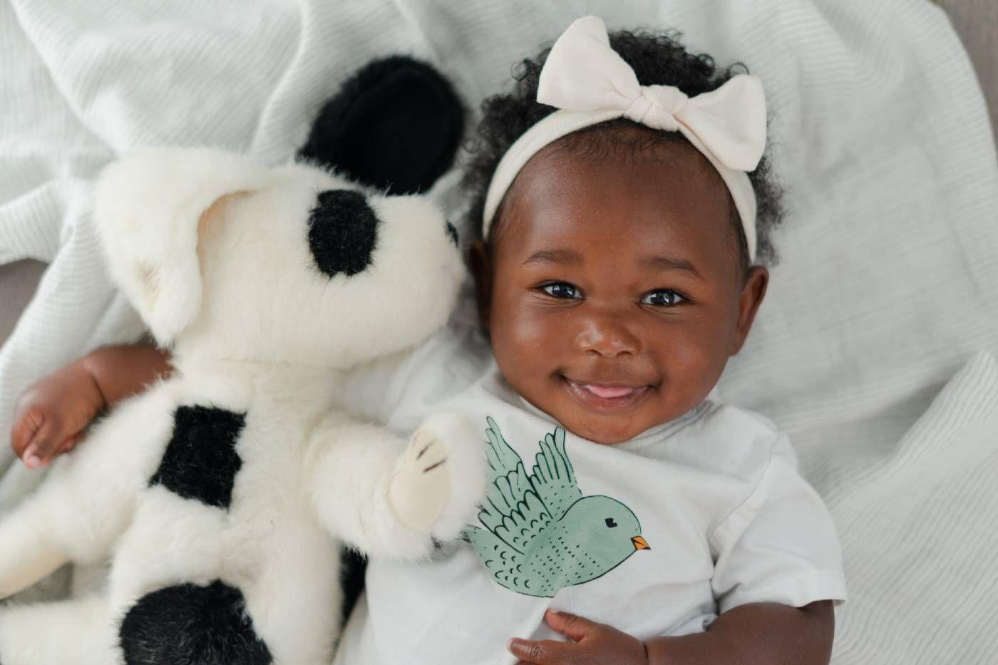 A baby smiles as she hugs her lovey