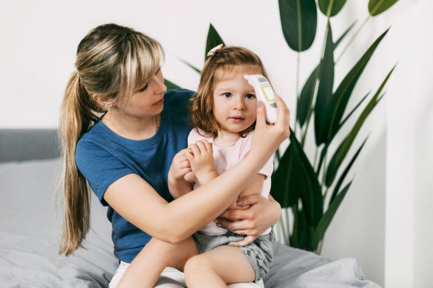 A mum takes her toddler's temperature