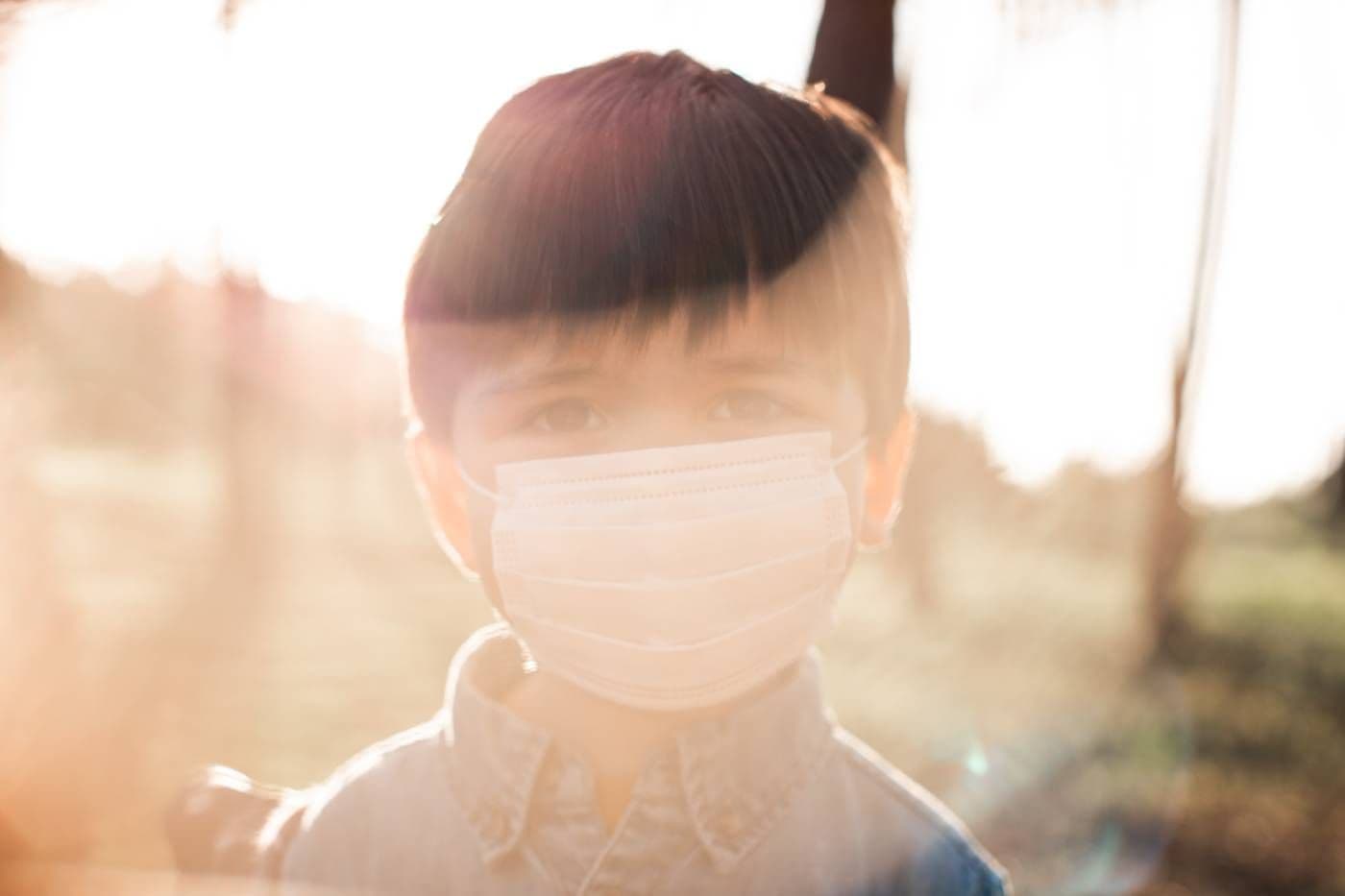 Child in mask outdoors due to wildfire smoke