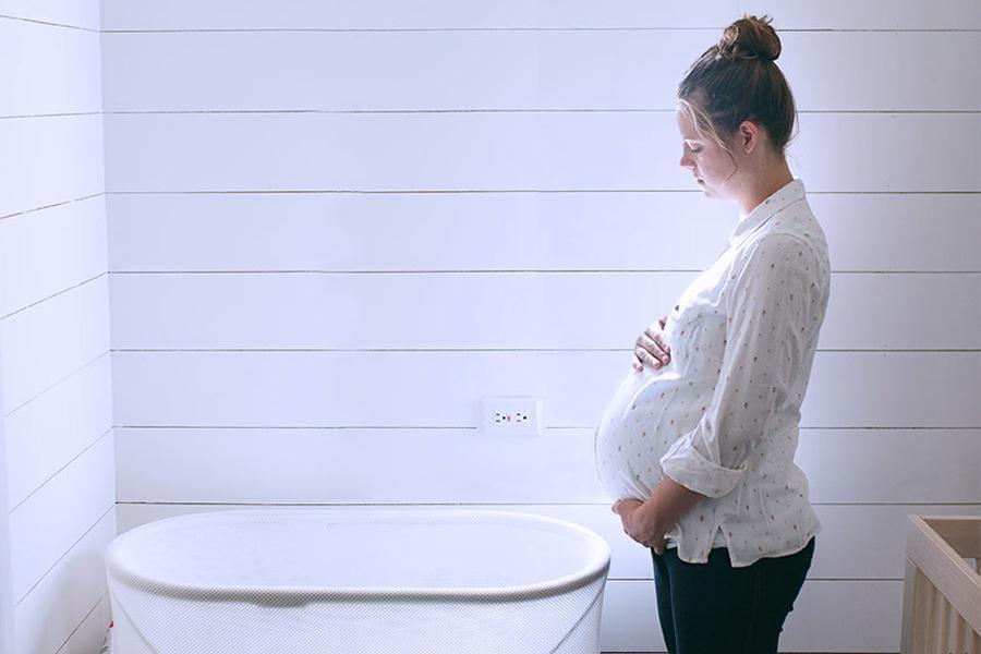 Pregnant woman standing beside the SNOO