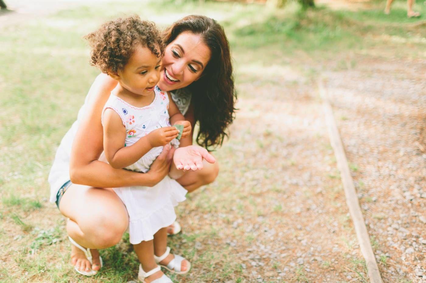 Smiling mom kneeling behind toddler